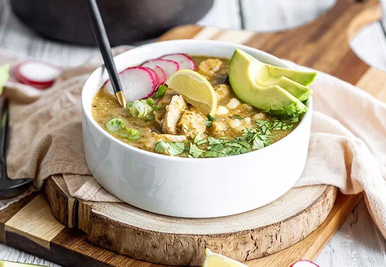 Una tazza della tradizionale zuppa messicana pozole con pollo, fette di avocado e ravanelli