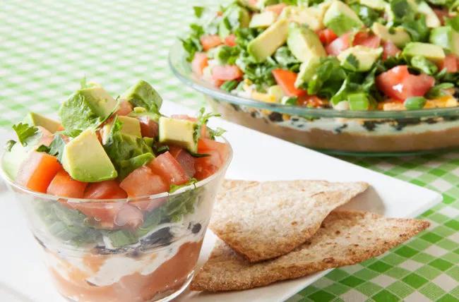 Insalata di taco a otto strati in tazza e in piatto da portata