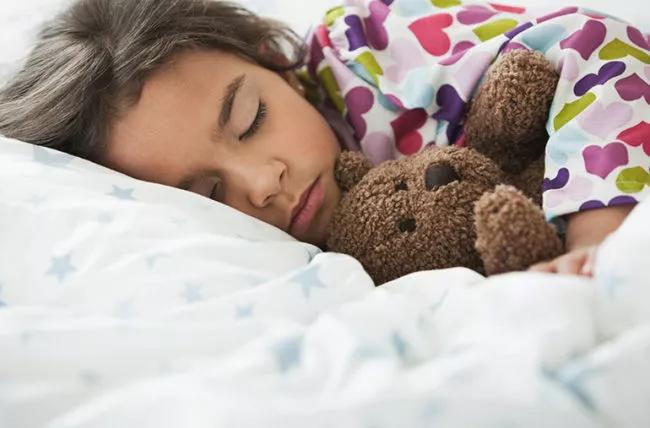 Un bambino che dorme con un orsacchiotto.