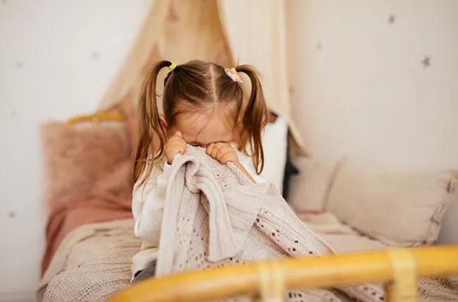 Un bambino nascosto dietro una coperta.