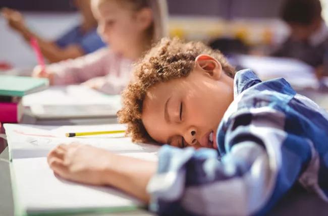 Un bambino che dorme in classe.