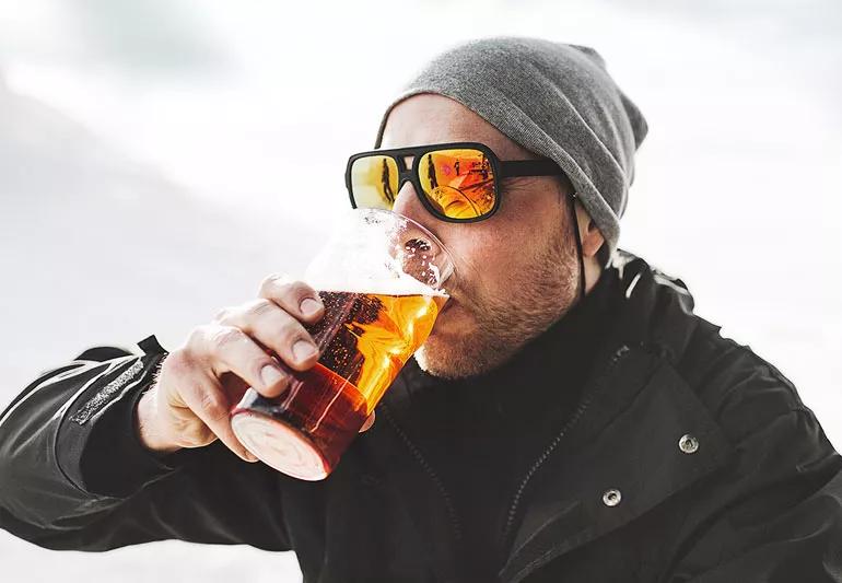 Uomo che beve una birra fuori durante l'inverno