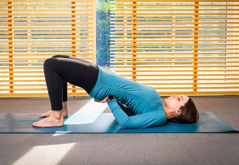 persona sul tappetino yoga in posizione del ponte supportato